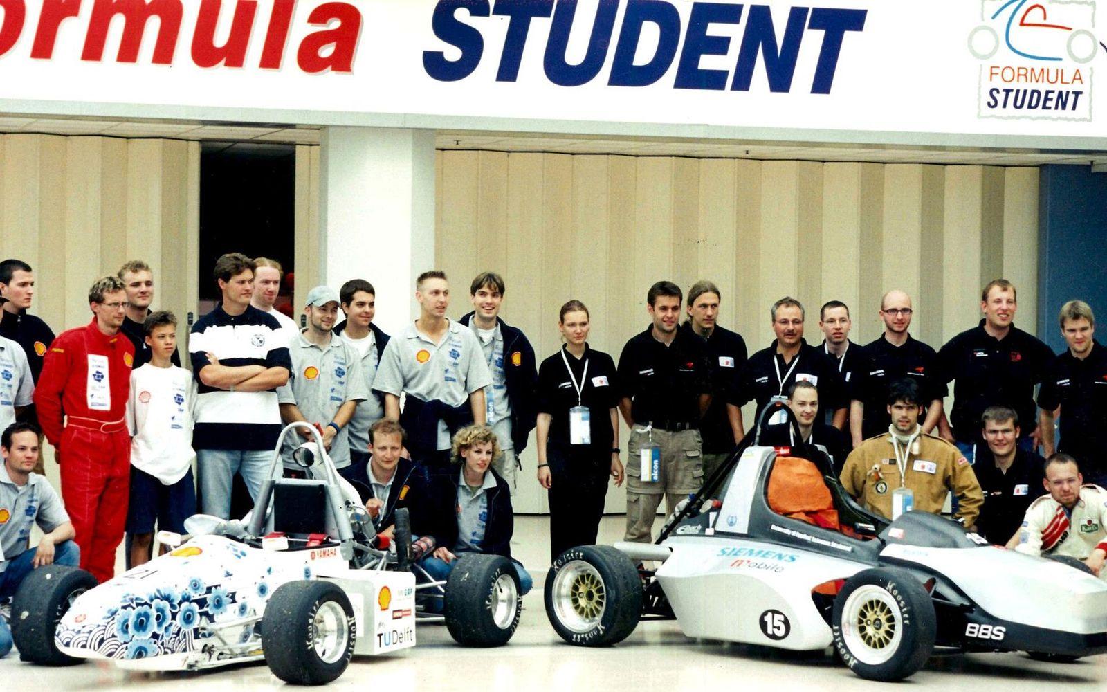 Delft University of Technology Formula Student team posing with their sponsor-liveried race cars